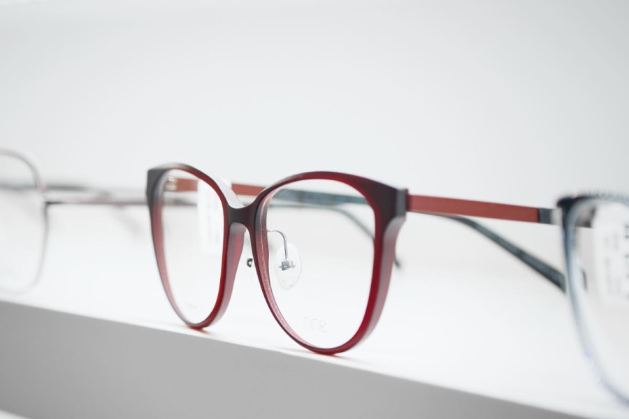 Seitenansicht einer dunkelroten Brille - elegantes Design mit unscharfem Hintergrund weiterer Modelle